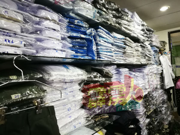 各尺寸校服陈列架子上，待学生前来选购。
