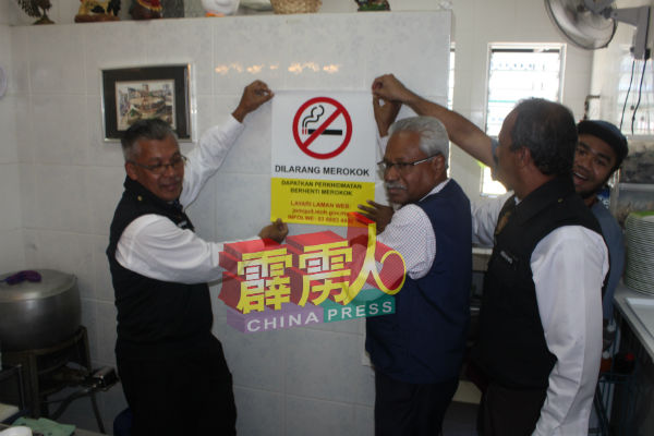 西华尼申（左2）等人在食肆内张贴禁烟告示。