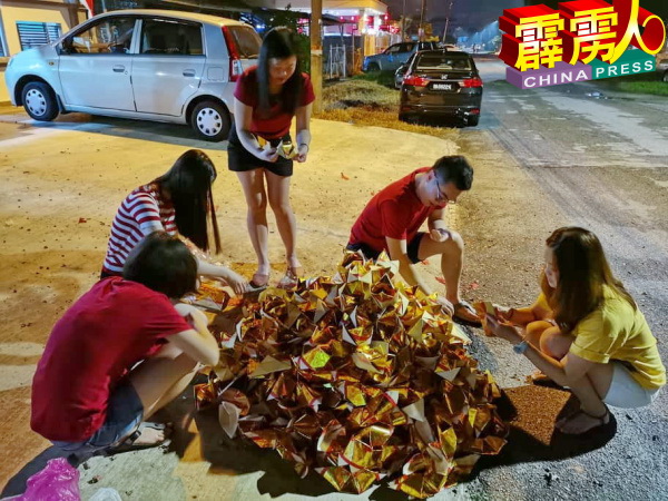 一家人围聚在一起,折叠金银纸。
