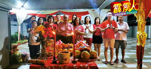 一家大小在神案前持香诚心膜拜,祈求大小平安风调雨顺。