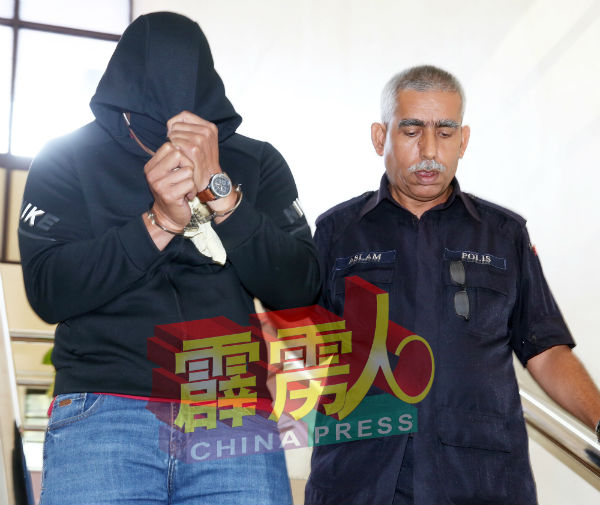 巫裔警长(左)以衣物盖头,由庭警押离法庭。