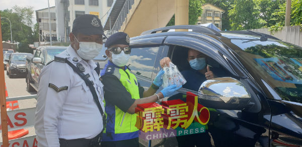 好心的民众途经路障时,送上搓手液给前线的军警。