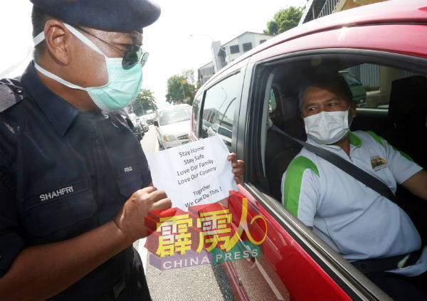 警方展示印有劝导式字眼的纸张,并呼吁民众留在住家。