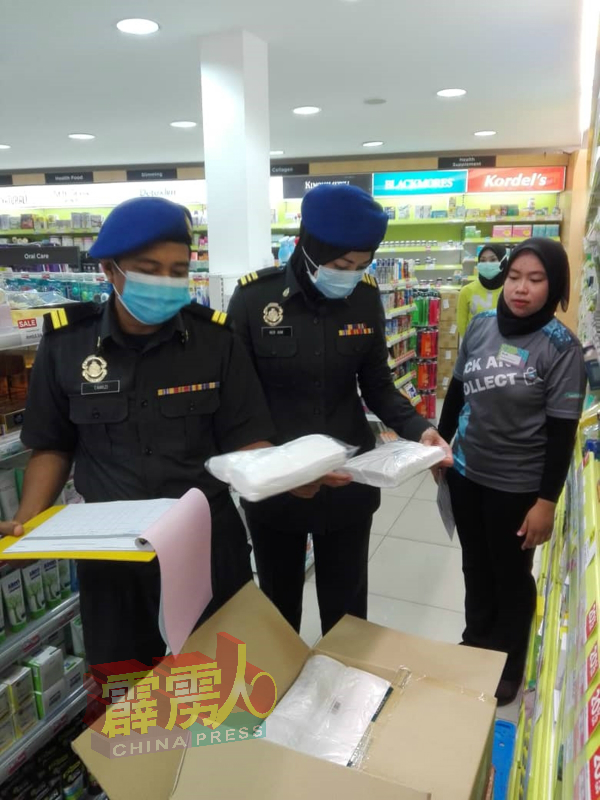2名执法人员检查店内,核对货品供应及价格是否符合条例。