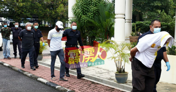 打高尔夫球被控无视行动管制的3名华裔男子,被警察押抵法庭面控时,以衣服及口罩遮脸。
