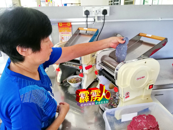 黄美珍以压面机搅出面条。