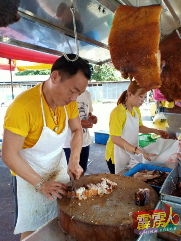 黄云添(左)快刀切肉,妹妹则协助包裹烧肉,兄妹俩合作无间。