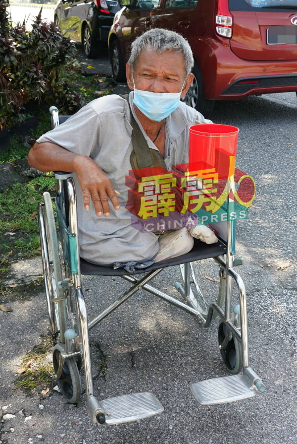 双腿截肢的老翁坐着轮椅在大路旁行乞。