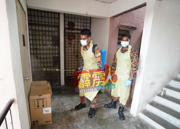 消拯员在铁门及走廊喷射消毒液。