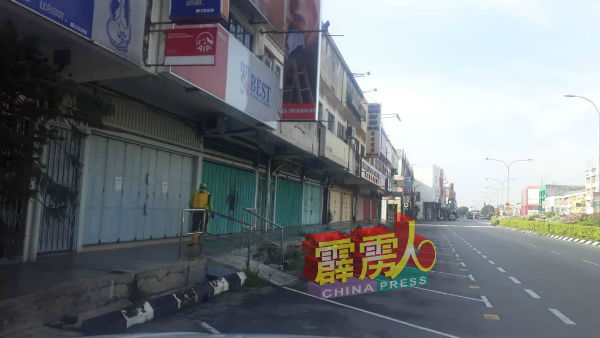 工作人员沿着商店走廊,进行消毒工作。