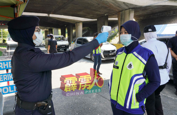 执勤前先检查体温！女警为前来路检执勤同僚检查有否发烧。