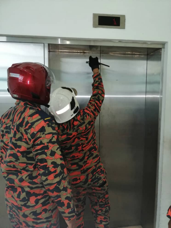 消拯人员动用工具,试图打开升降机门。