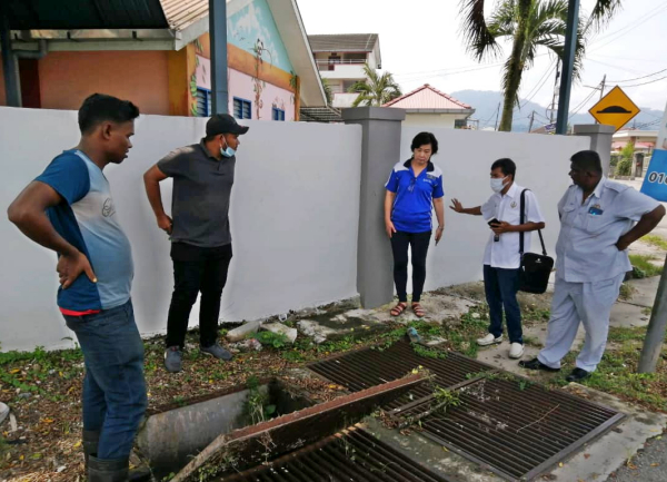 市议会工程官组官员前来学校,一行人现场研究解决沟渠阻塞问题。