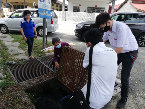 廖泰义(左2)在助理协助下,掀开沟铁盖视察弊病导因,左为王丽娟。