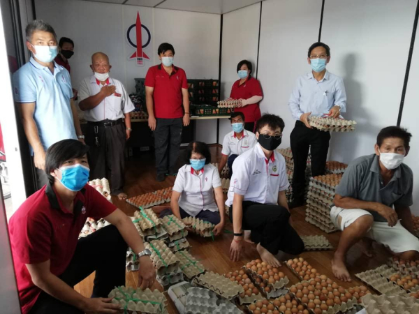 廖泰义(右2站者)在服务中心团队协助下,整理妥当鸡蛋准备派送选区有需要民众。