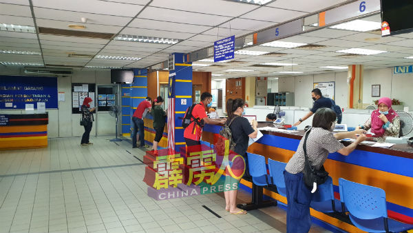 民众在柜台办理事务时,保持安全距离。