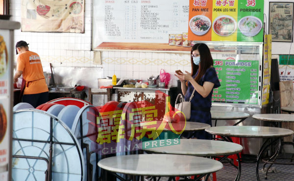 顾客在打包食物时,皆遵受条例,除了戴口罩,在排队时也保持社交距离。