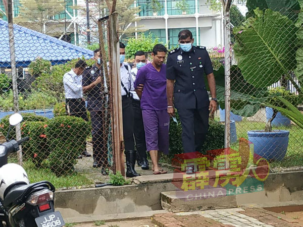被告(中)在警员的押送下,步入江沙地庭。