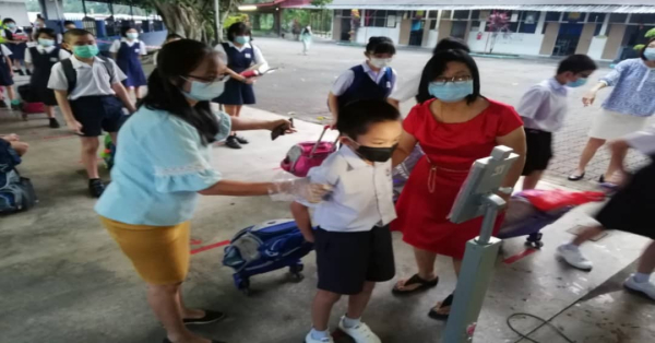 学生列队轮流接受人脸识别仪检测。