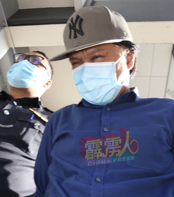 被告被押往法庭面控时,低头迴避摄影记者的镜头。