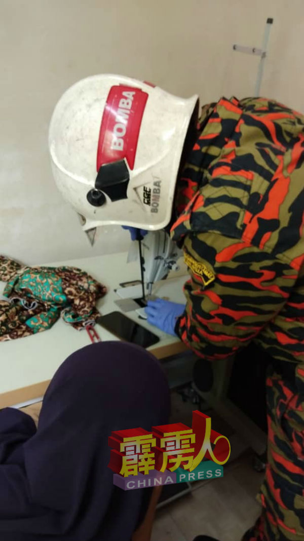 消拯员用特殊器具协助妇女大拇指移离缝纫机。