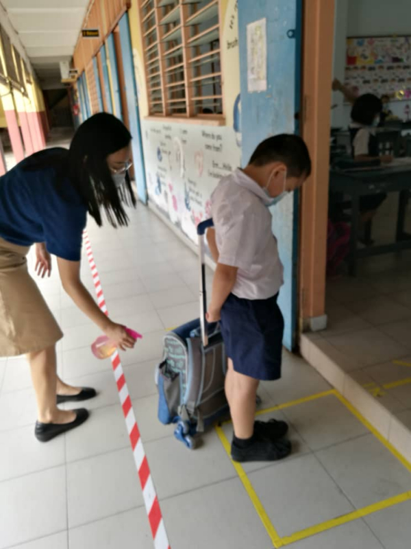 学生踏进课室前，书包须喷射消毒剂。
