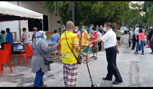 陈毅贤（右起）看见病患者需拿拐杖行路，建议其家属代为排队领验血号码，以让患者可在等候区休息。
