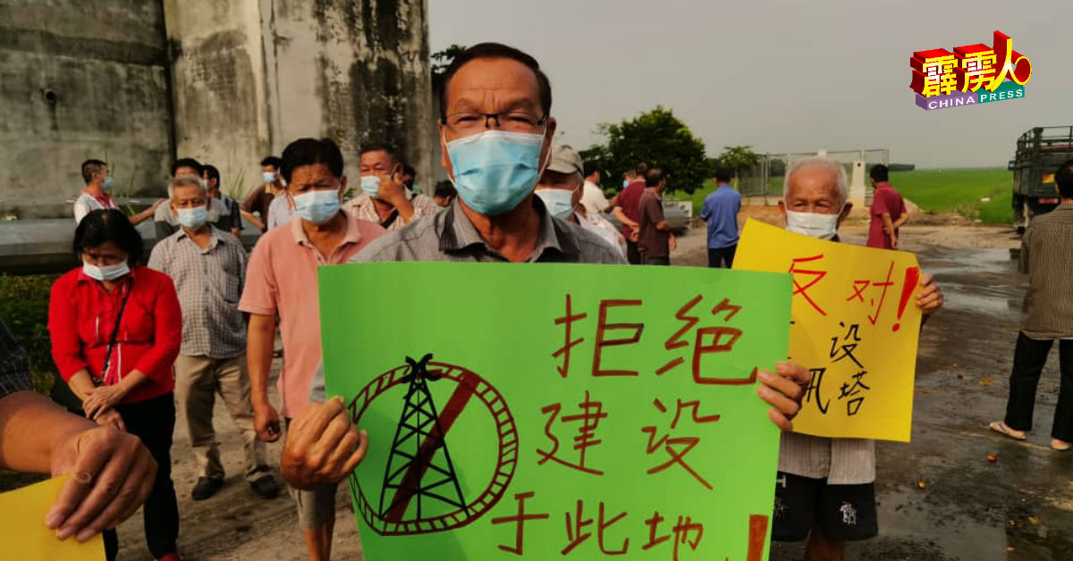 刘顺（中）持大字报反对电讯塔建在路口处。