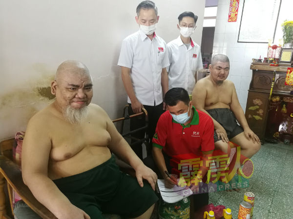 植旷荣（中）为李智光（左起）及李智宏登记个人资料，协助2兄弟申请福利局援助金。