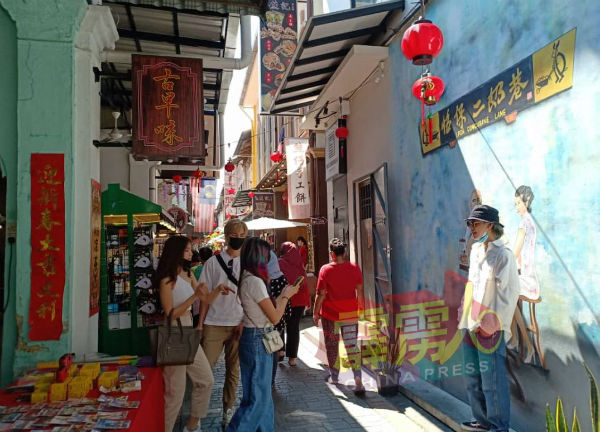 政府开放国内旅游后，二奶巷吸引不少来自国内游客到访，其中一些游客在壁画前留影。