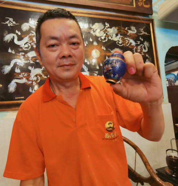 柯文德展示娘惹先人使用的景泰蓝瓶子。