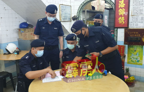 依祖安（坐者左）发出罚单给没遵守标准作业程序的业者。