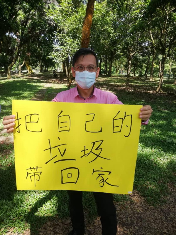 廖泰义展示手上的“把自己的垃圾带回家”标语，鼓励民众响应。