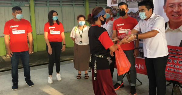 吴家良（右）代表倪可敏派發旺财猪手予安顺民众，左起卢裕纹、陈俐伶、王贤勋、陈苏州和林建龙。