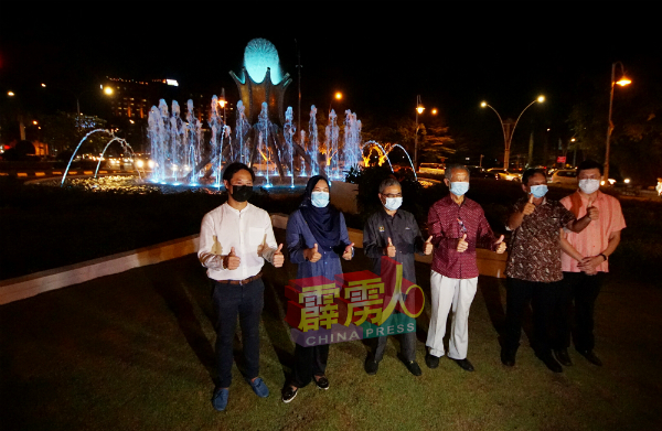 诺丽（左2起）在鲁迈兹、刘瑞裕、刘佑唯（左）等下陪同下，在怡保夜光杯交通圈喷水池前合影。