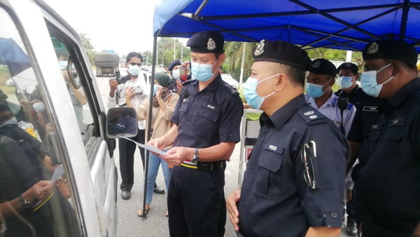 吴文恭检查一名司机的文件,左为吉辇警区主任玛祖基