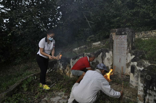 寻获墓碑后,梁惠雰(左起)、梁亚玖及曾庆发点火烧香祭拜先人,以慰先人在天之灵。