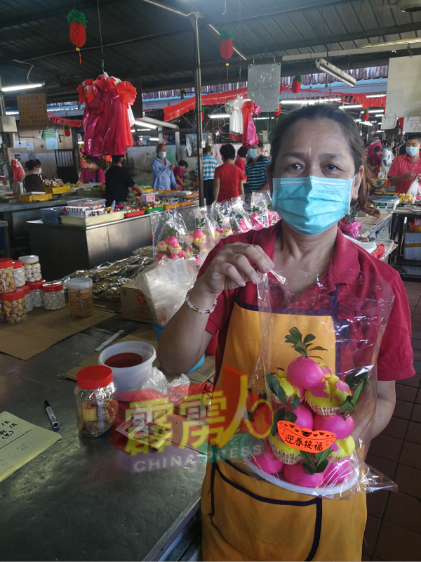 吕美丽（年饼小贩）手持“迎春发糕”，祝贺新年。