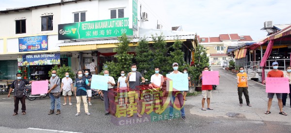 巴占新市镇约15名商家，举起写有“受不了”等字眼的手写卡，希望地方政府能够尽快解决该处排污的问题。