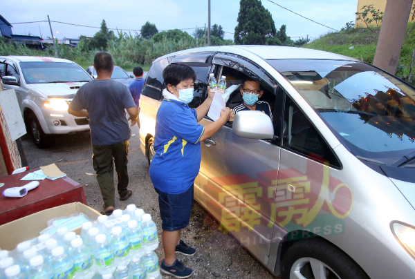 拿乞列圣宫义山入口处，义山保管委员会成员，确保民众遵守标准作业程序，并送上矿泉水及口罩。