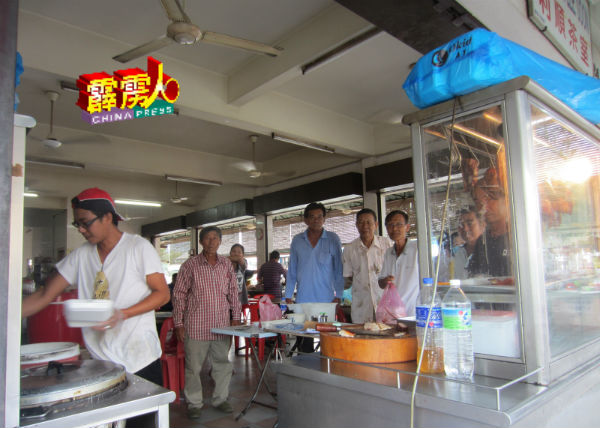 邦新村利顺茶室的烧肉烧鸡饭摊，从上午11时开摊，就有人排队等待购买，也是东主黄振达（右） 忙得不可开交的时刻。