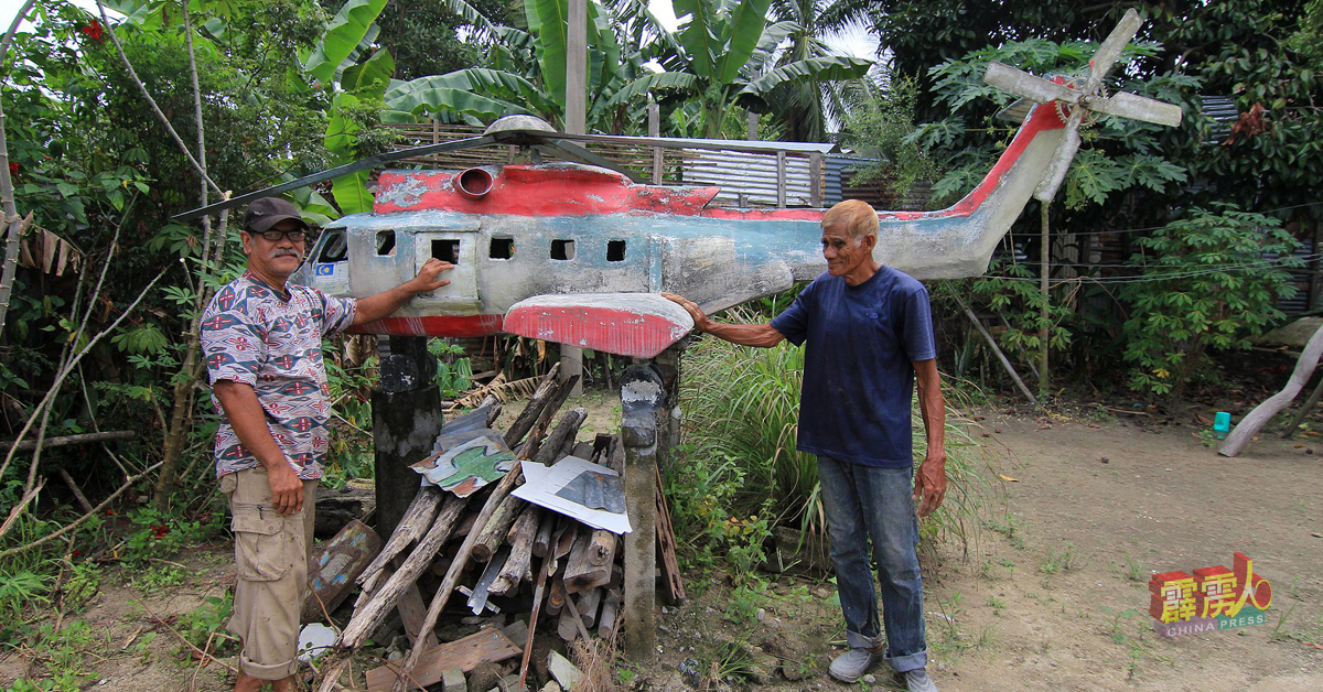 聋哑胶工“巴丁”无师自通下，用水泥创作出海陆空交通工具，包括这架救灾直升机，成为万浓甘榜乌鲁标居民的骄傲，右为邻居“巴曼”。

