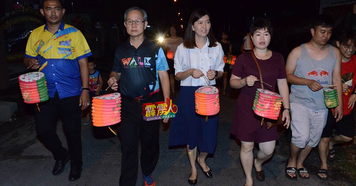 李文材（左2起）、黄诗情、温美娇带领村民提灯游行。