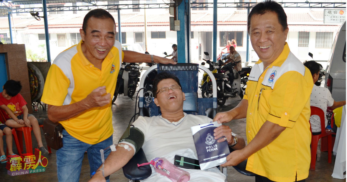 侯信用（右）和蔡顺杰（左）赠送纪念品给捐血民众。