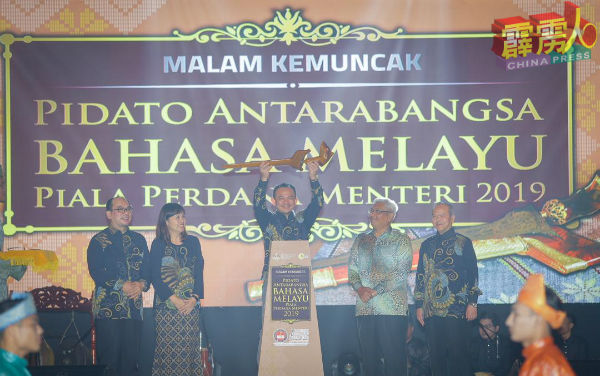 马智礼（中间）高举马来短剑，为2019年首相杯国际马来文演讲比赛主持开幕仪式，陪同者有莫哈末沙塔（左起）、张念群、阿都阿兹巴里、莫哈末嘉扎里。