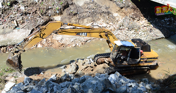 挖土机正在如火如荼的在22号街通往峇鲁路的桥梁下安装抛石护岸。