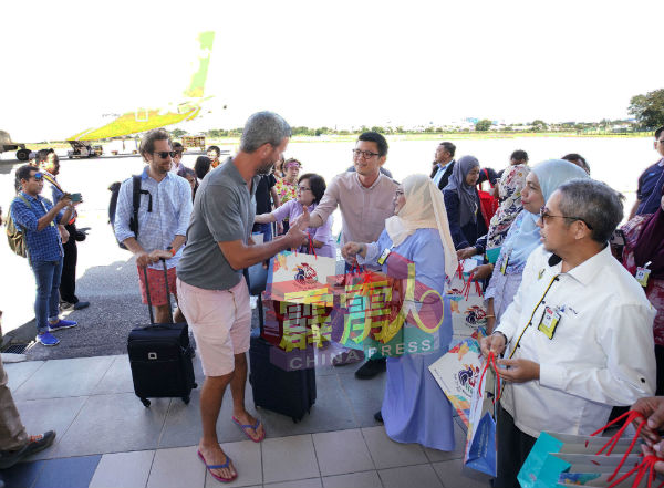 陈家兴（右3）在机场处分派礼品包给到访怡保的游客。