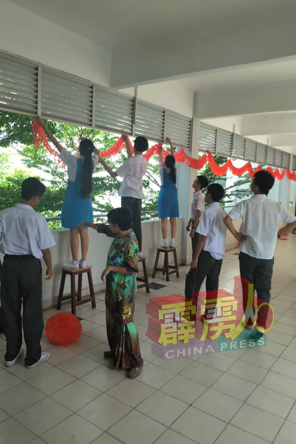 育才华中的师生们，忙碌的把灯笼挂在走廊的高处。