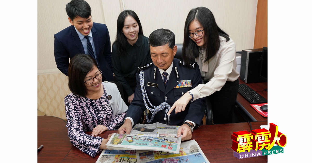 荣休的林鸿选与妻子李美霞及子女分享《中国报》的报导；站者为林新柔、林欣怡及林松毅。