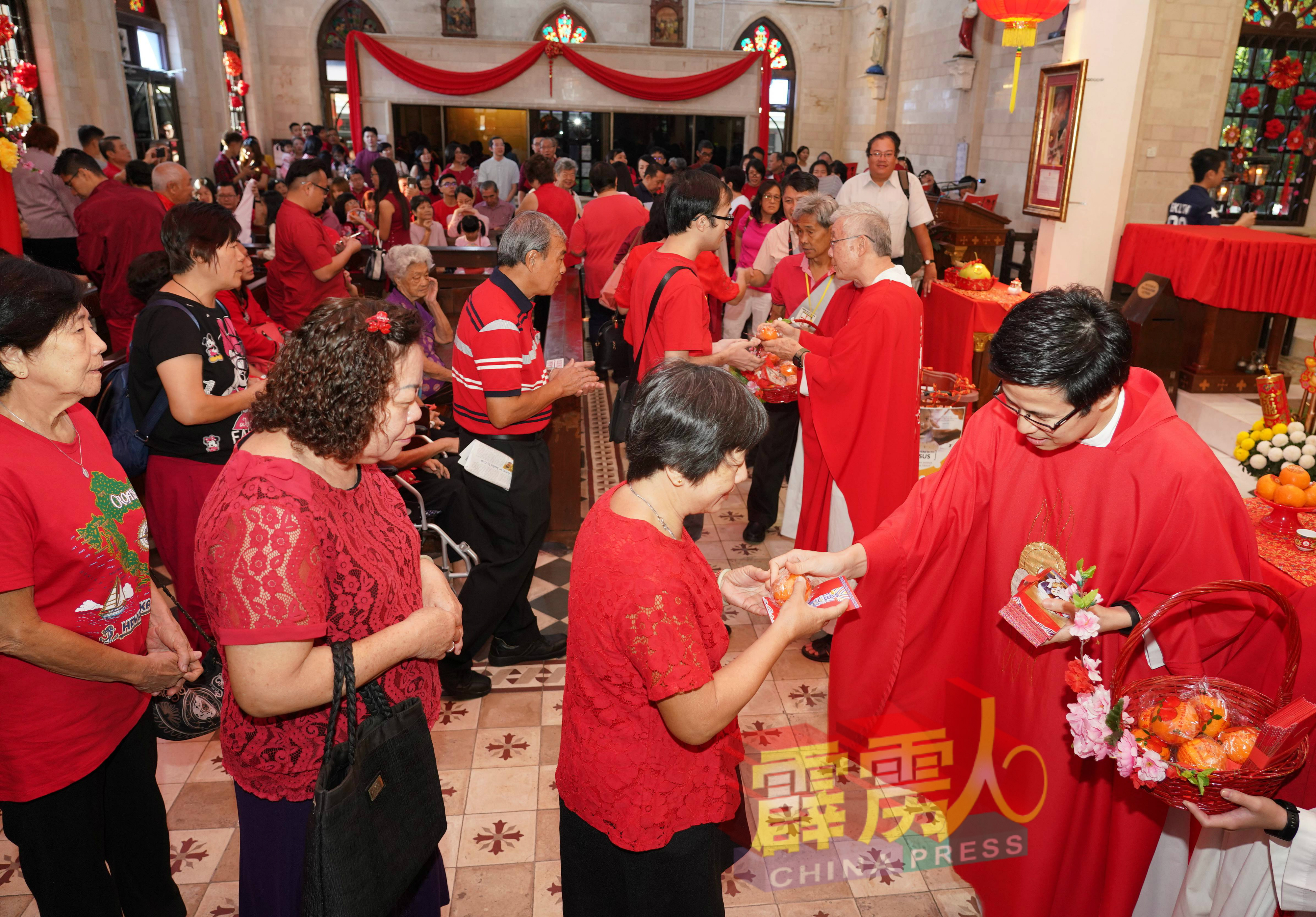 刘善财神父派发红包及年柑给教友，彼此共庆新春佳节。